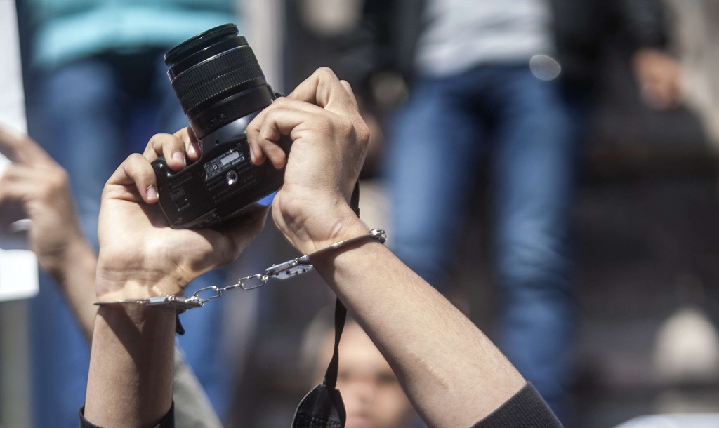 A photojournalists with his mouth tapped holds up his camera as he demonstrates with fellow colleagues in front of the journalist's syndicate in Cairo against repeated attacks on members of the press in Egypt on April 4, 2014. AFP PHOTO / MAHMOUD KHALED?